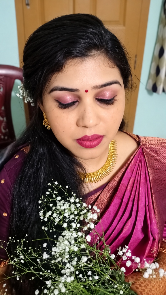 Luminous bridal makeup close-up with champagne-pink shimmer eyelids and baby's breath floral hair styling
